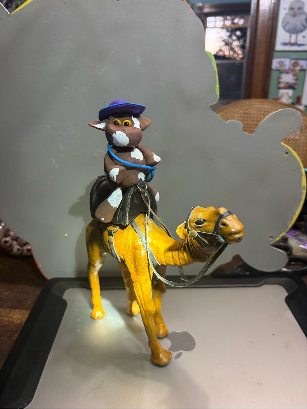 Mrs. Cow riding a camel through the desert